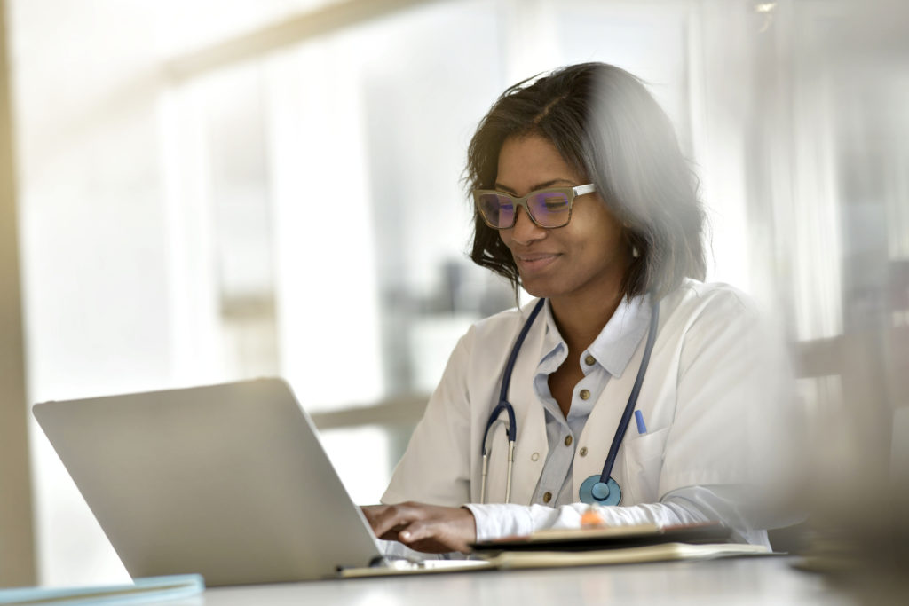 Woman doctor working in office with laptop